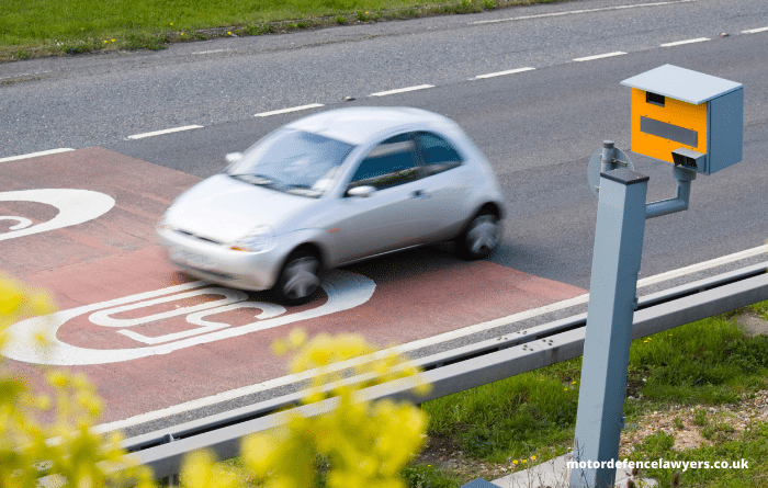 Car entering a new speed zone on road in front of speed camera